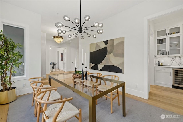 dining area featuring light hardwood / wood-style floors, wine cooler, and a chandelier