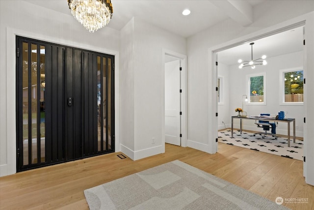 foyer entrance featuring hardwood / wood-style floors, a notable chandelier, and beam ceiling