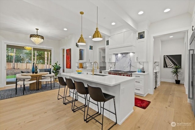 kitchen with white cabinets, light hardwood / wood-style floors, sink, and hanging light fixtures