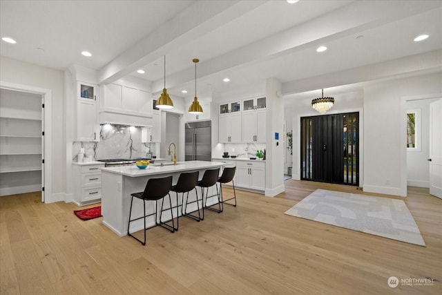 kitchen with light hardwood / wood-style floors, white cabinetry, hanging light fixtures, and appliances with stainless steel finishes