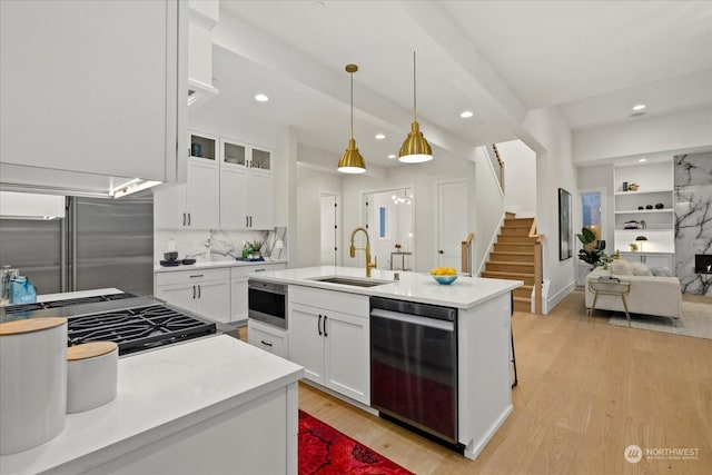 kitchen featuring appliances with stainless steel finishes, sink, decorative light fixtures, light hardwood / wood-style flooring, and white cabinetry