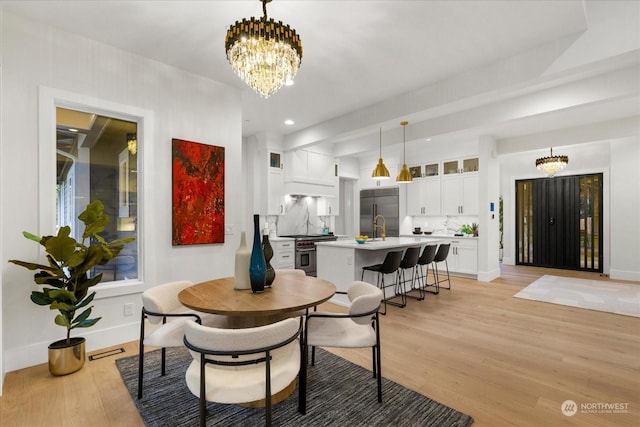 dining area featuring sink, a chandelier, and light wood-type flooring