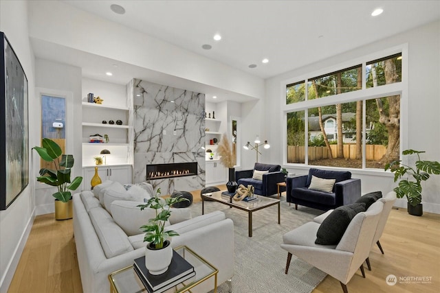 living room with built in shelves, a premium fireplace, and light hardwood / wood-style floors