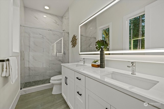 bathroom featuring hardwood / wood-style floors, vanity, a shower with shower door, and toilet