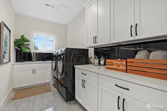 clothes washing area with cabinets, sink, light hardwood / wood-style flooring, and independent washer and dryer