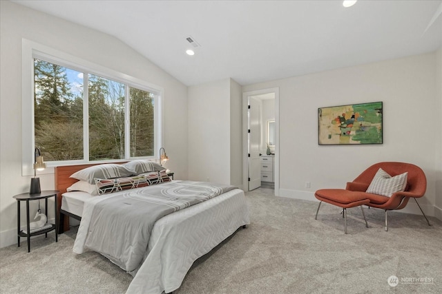 bedroom featuring ensuite bath, light carpet, and vaulted ceiling