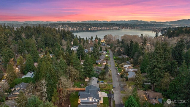 aerial view at dusk featuring a water and mountain view