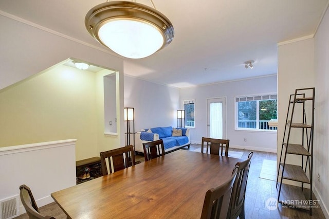 dining area with wood-type flooring and ornamental molding