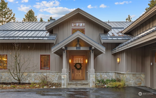 entrance to property featuring board and batten siding, stone siding, metal roof, and a standing seam roof