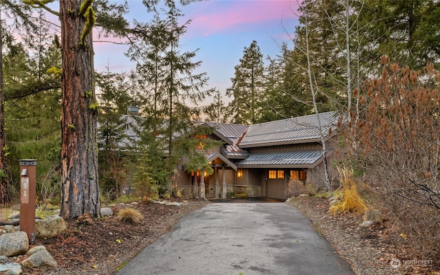 view of front of house with board and batten siding, a standing seam roof, metal roof, stone siding, and driveway