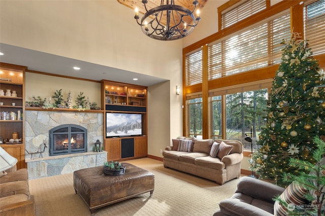 living room with built in shelves, a towering ceiling, a chandelier, light colored carpet, and a fireplace