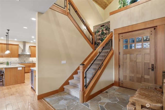 staircase featuring high vaulted ceiling, recessed lighting, stone finish flooring, and baseboards