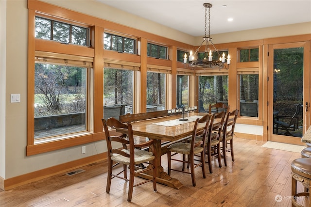 dining area with light wood finished floors, an inviting chandelier, visible vents, and baseboards