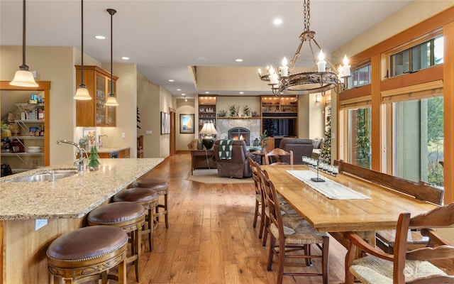 dining room featuring a chandelier, a fireplace, light hardwood / wood-style floors, and sink