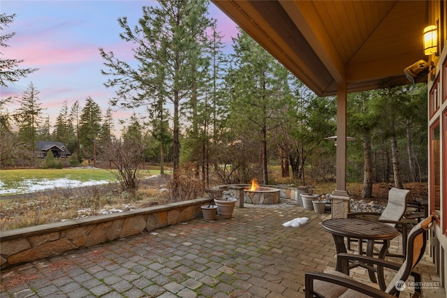 patio terrace at dusk featuring a gazebo, a water view, and an outdoor fire pit