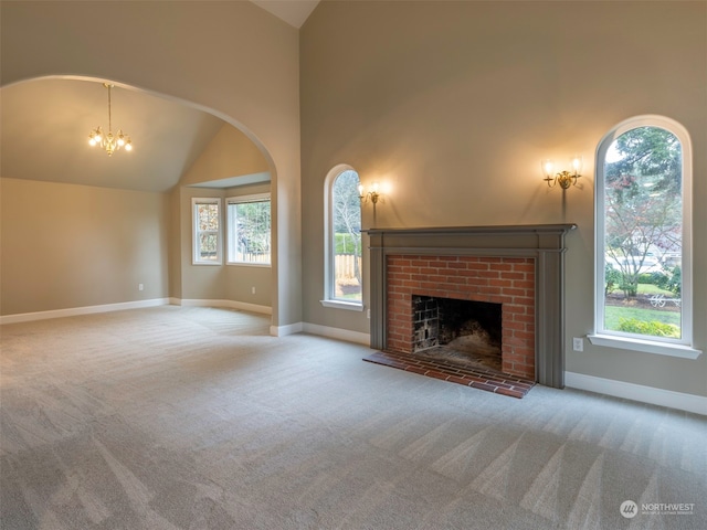 unfurnished living room featuring carpet, a notable chandelier, a fireplace, and high vaulted ceiling