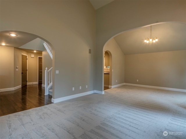 carpeted spare room with lofted ceiling and an inviting chandelier