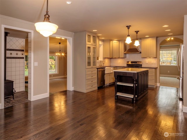 kitchen featuring appliances with stainless steel finishes, wall chimney exhaust hood, pendant lighting, a kitchen island, and plenty of natural light