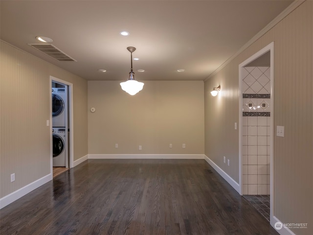 spare room featuring ornamental molding, dark hardwood / wood-style floors, and stacked washer and clothes dryer