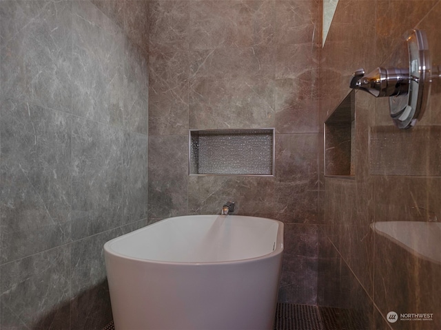 bathroom with a bath and tile walls