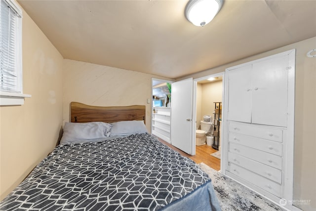 bedroom with connected bathroom and wood-type flooring