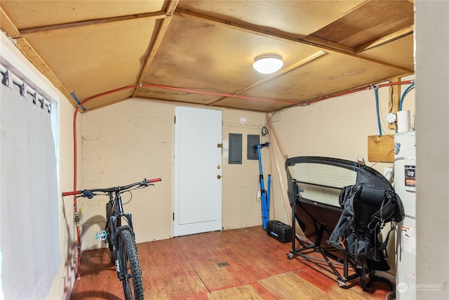 exercise room with electric panel, hardwood / wood-style flooring, vaulted ceiling, and water heater