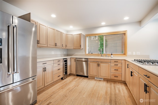 kitchen featuring sink, light wood-type flooring, light brown cabinetry, stainless steel appliances, and beverage cooler