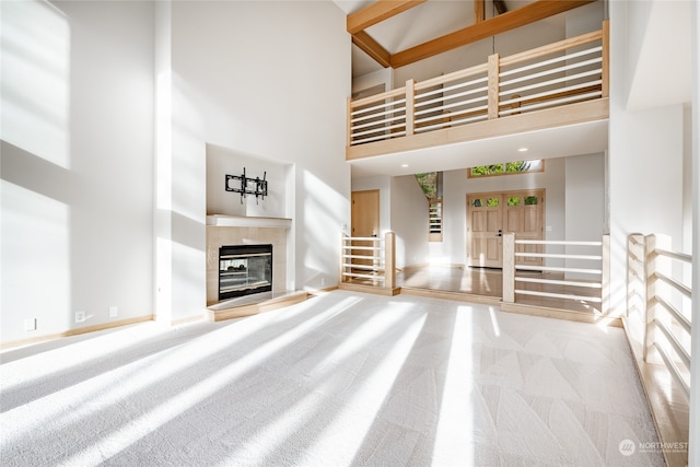 unfurnished living room with a tile fireplace, carpet, and a towering ceiling