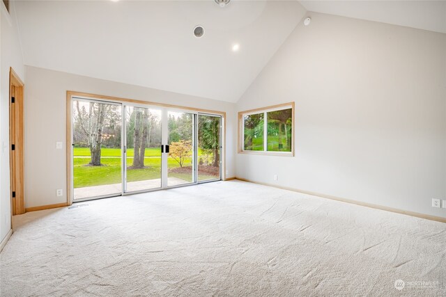 carpeted spare room featuring high vaulted ceiling