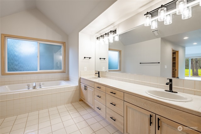 bathroom featuring tile patterned flooring, vanity, tiled bath, and vaulted ceiling