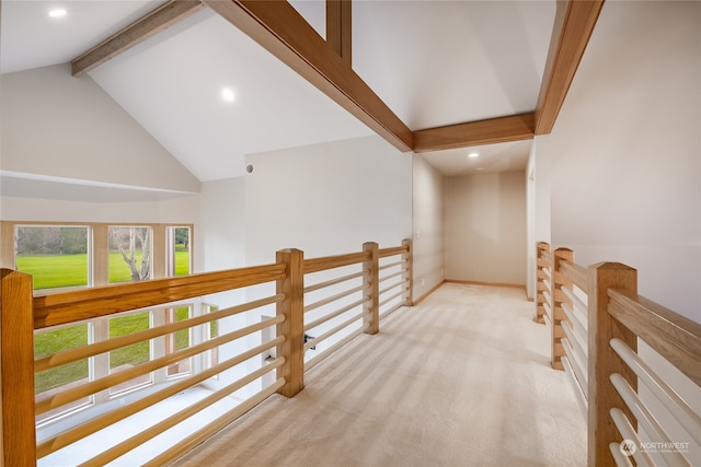 hallway with beam ceiling, light colored carpet, and high vaulted ceiling