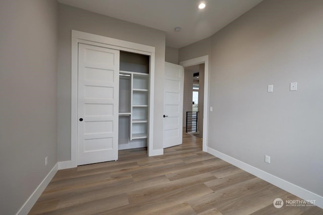 unfurnished bedroom with light hardwood / wood-style flooring and a closet