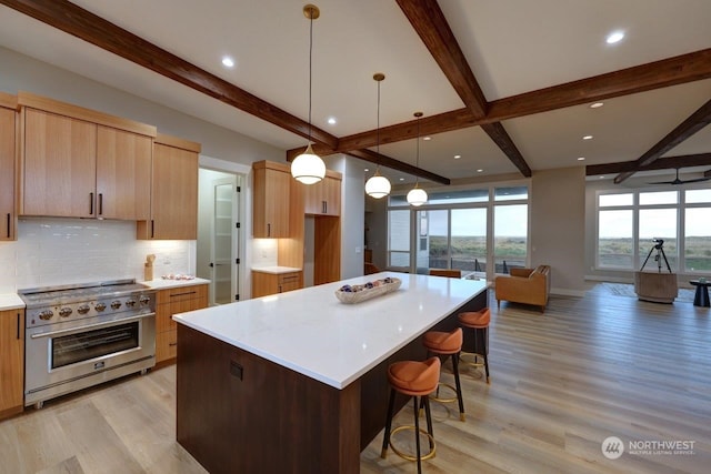 kitchen with decorative backsplash, high end stove, beam ceiling, light hardwood / wood-style flooring, and a kitchen island