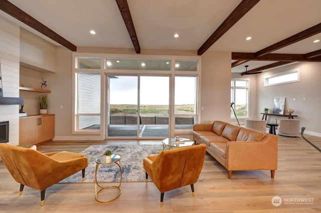 living room with a fireplace, beamed ceiling, and light hardwood / wood-style floors