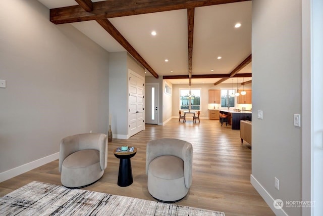 sitting room with beam ceiling, an inviting chandelier, and light wood-type flooring