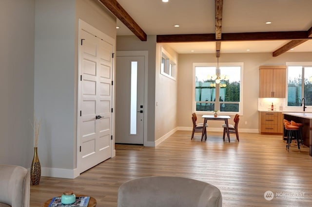 foyer featuring a chandelier, hardwood / wood-style floors, sink, and beam ceiling