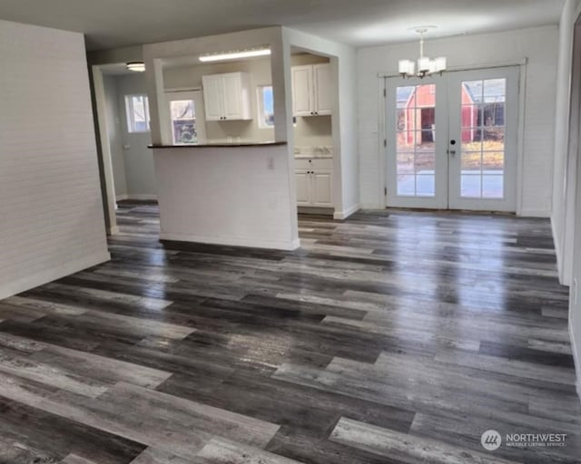 unfurnished living room featuring french doors, dark hardwood / wood-style floors, and an inviting chandelier