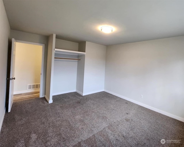 unfurnished bedroom with dark carpet and a closet