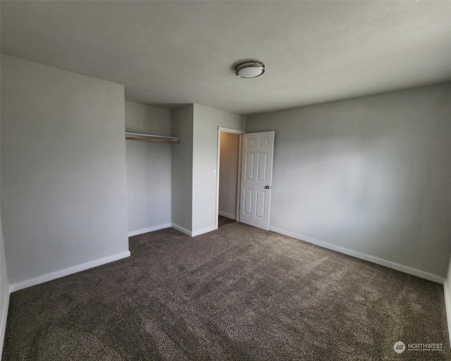 unfurnished bedroom featuring dark colored carpet and a closet