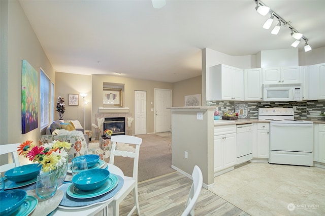 kitchen featuring white appliances, a tile fireplace, tasteful backsplash, light hardwood / wood-style floors, and white cabinetry