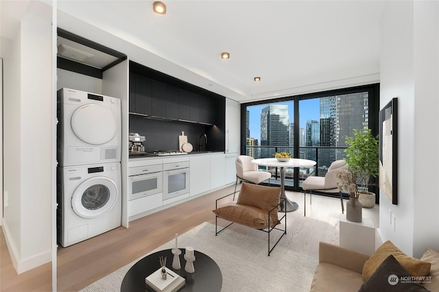 interior space with stacked washer and dryer, floor to ceiling windows, sink, and light hardwood / wood-style floors