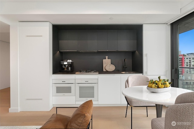 kitchen with white cabinets, tasteful backsplash, sink, and oven