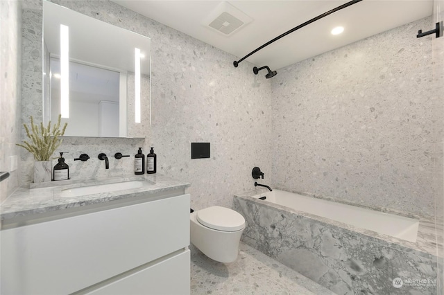 bathroom with tile walls, vanity, and shower / bathtub combination