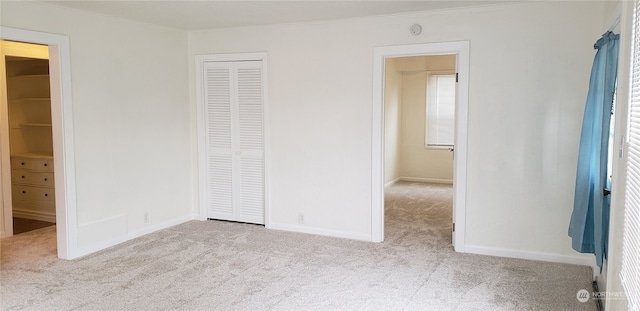 unfurnished bedroom featuring light carpet and a closet