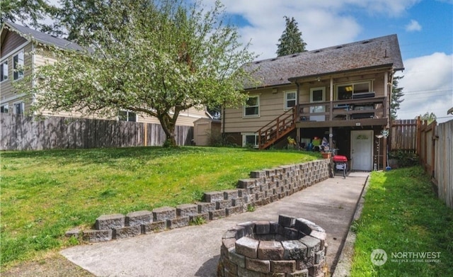 back of house featuring a yard, a fire pit, and a deck