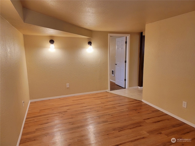 unfurnished room with a textured ceiling and light hardwood / wood-style floors