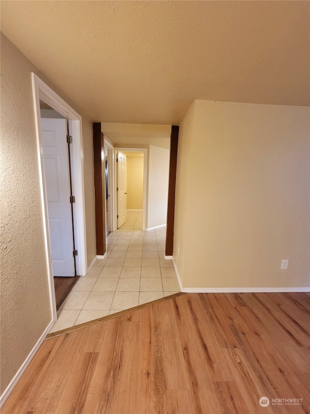 hallway featuring light hardwood / wood-style floors and a textured ceiling