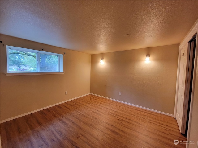 unfurnished room featuring hardwood / wood-style floors and a textured ceiling