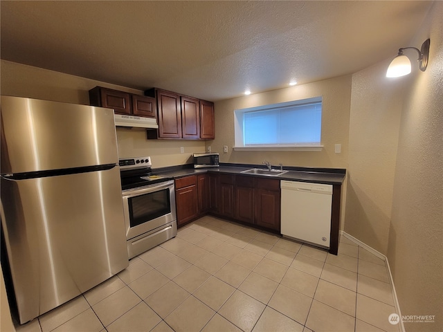 kitchen with appliances with stainless steel finishes, a textured ceiling, light tile patterned floors, and sink