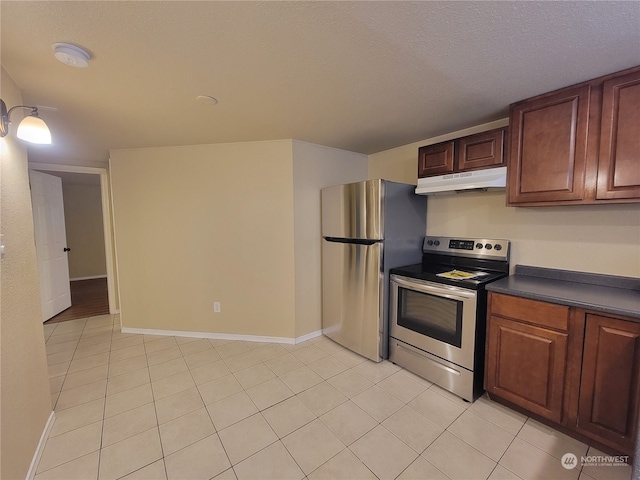 kitchen with a textured ceiling, light tile patterned floors, and stainless steel appliances